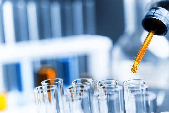 Dropping sample to test tube containing chemical liquid in laboratory, lab chemistry or science research and development concept