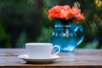 A beautiful set of white coffee mugs on a wooden table in a natural setting in the morning.