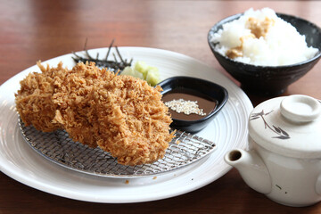 close-up of HireKatsu, Japanese pork cutlets on a black plate with delicious flavourful miso sauce on a bamboo mat