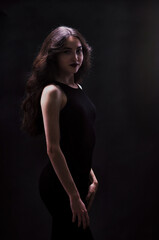 Fototapeta premium Silhouette of a beautiful, slender brunette in a black dress