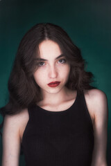 Portrait of a young brunette with lush wavy hair and beautiful highlights in the eyes