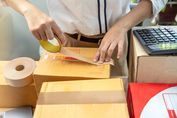young start up small business owner packing cardboard box at workplace. freelance woman seller prepare parcel box of product for deliver to customer. Online selling, e-commerce,