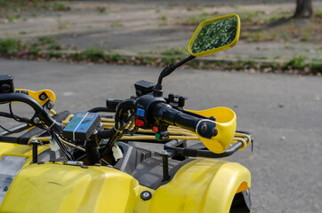 Close-up of steering wheel and rearview mirrors of an quad bike in parking lot.