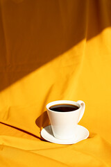 White cup of hot coffee in summer light.