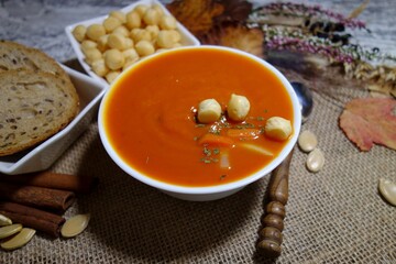 Pumpkin cream soup.  Tasty and nutritious pumpkin soup in white bowl and croutons and puff pastry - selective focus