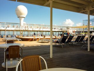 People relaxing in the sun on pool deck of luxury cruiseship or cruise ship liner on sun loungers