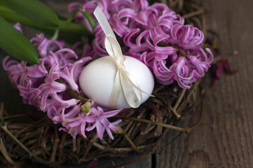 Happy easter card. on a dark wooden background on a wicker wreath: flowers of pink hyacinth, egg