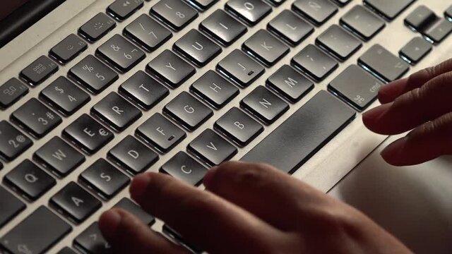 Close up of female hands typing on a laptop keyboard.