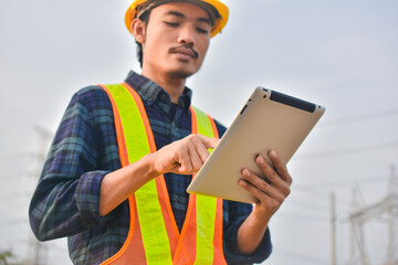 Engineer holding tablet outdoor high voltage system background