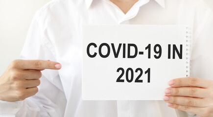 The doctor points to a notebook with COVID-19 IN 2021.