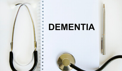 In the notebook is the text of DEMENTIA, next to it is a stethoscope and a pen. Medic concept.