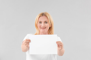 Naklejka premium Woman with blank paper sheet on grey background