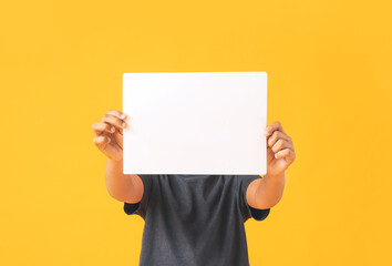 Little African-American boy with blank paper sheet on color background