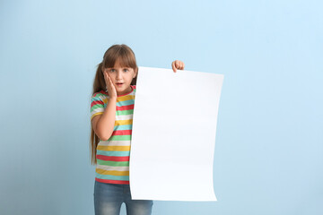 Surprised little girl with blank paper sheet on color background