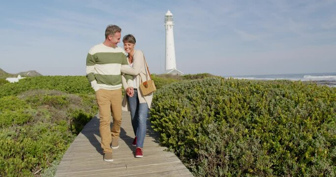 Caucasian couple enjoying free time by sea on sunny day walking path