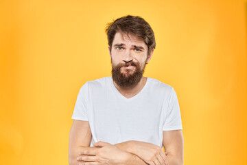 A man in a white t-shirt gestures with his hands studio lifestyle yellow background emotions