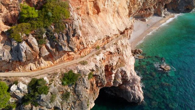 Aerial: amazing coastal walkway path along Croatian cliffs on Adriatic Sea with turquoise water