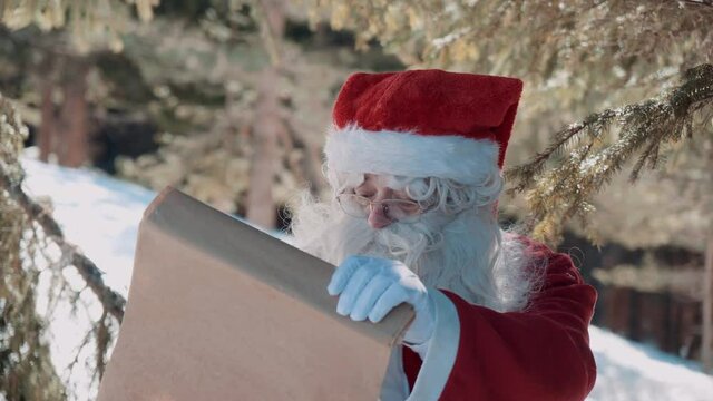 Santa is looking at a scroll with presents for the children.
Outside under the shade of a pine tree.