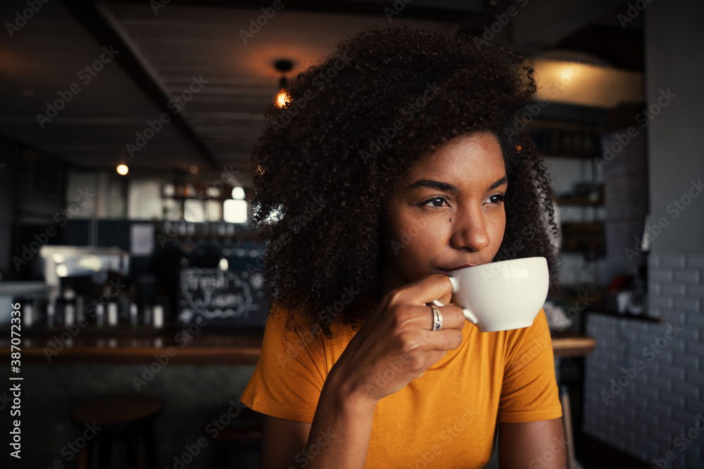 Wall mural ethnic female sipping hot coffee relaxing in rustic restaurant