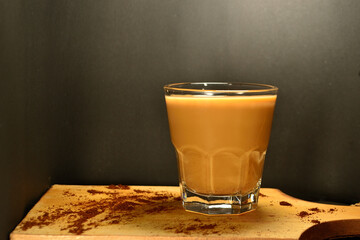 a glass of coffee milk on a black background