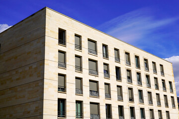 corner of modern building with many windows against the blue sky and cloud