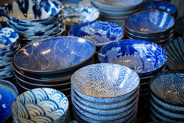 An isolated, slightly downward, view of stacks of blue and white patterned porcelain bowls
