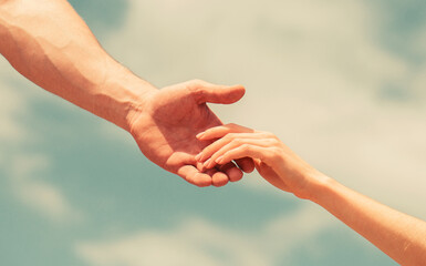 Hands of man and woman on blue sky background. Lending a helping hand. Solidarity, compassion, and...