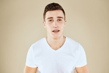 Obraz premium Emotional man and white t-shirt gesturing with hands beige cropped background
