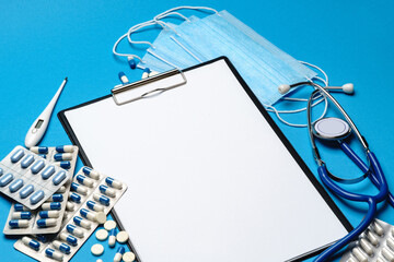 Empty clipboard with medical supplies - pills, protective masks, stethoscope and thermometer