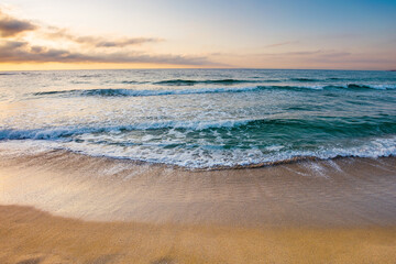sunrise at the sea. beautiful summer landscape on the sandy beach. green waves rush on the shore in golden light