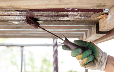 A worker paints a wooden ceiling