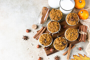Wooden tray with vegan pumpkin muffins, cinnamon and fresh pumpkins on light concrete background. Autumn of winter baking. Top view.