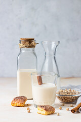 Chickpea vegetarian milk in a bottle and glass and raw chickpeas on light stone background. Lactose free non dairy products. Healthy vegan food concept.