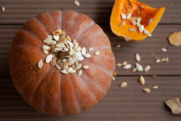 Round orange pumpkin and leaves on planks. View from above
