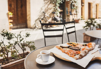 Vacations in Italy. Cup of espresso coffee with slices of pizza with beautiful italian street on the background.