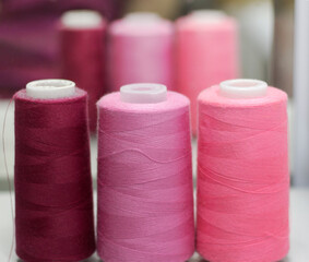 sewing threads in pink shades stand in a row against the background of the mirror in the Studio