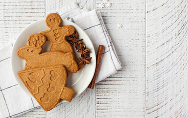 Christmas background with ginger cookies and spices on a light wooden background. Copy space.