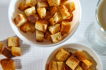 Square toasted pieces of homemade delicious rusk, hardtack, Dryasdust, zwieback in a plate on a white tablecloth.