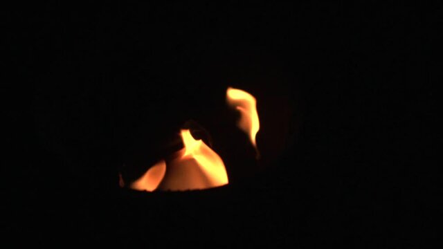 The fire burns on a torch wick on a black background, fire show. Slow motion