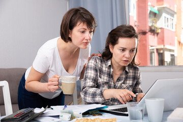 Women working with documents while working at laptop at home interior