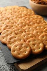 Obraz na płótnie Canvas Board with cracker biscuits on gray background