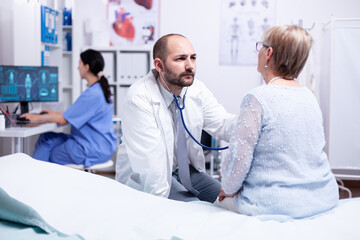 Fototapeta premium Elderly woman doctor appointment gets heart beat checked with stethoscope. Medical consultation for senior pensioner. Health care medicine system, physician treatment