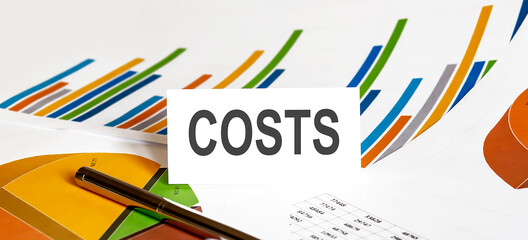 COSTS text on paper on chart background with pen