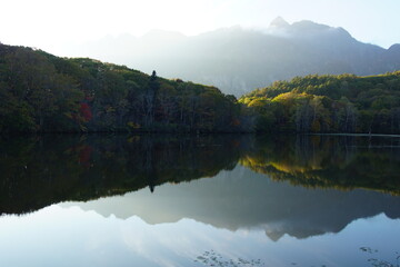 Fototapeta premium A pond that reflects trees and mountains like a mirror. At dusk. Beautiful scenery of Japan.
