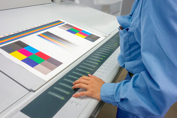 オフセット印刷において印刷物の濃度を測定する手元のアップ。カラーマネージメント、品質管理イメージ - obrazy, fototapety, plakaty