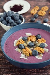 Acai smoothie bowl topping with walnut, coconut chips, chia seeds and blueberries
