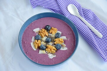 Acai smoothie bowl topping with walnut, coconut chips, chia seeds and blueberries