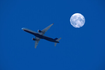airplane flight against the full moon and night sky, aviation and travel concept