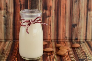 Almond milk with almond nuts on wooden table. Negative space

