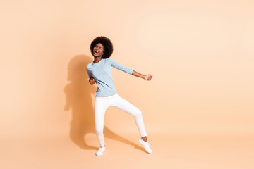 Fototapeta na wymiar Photo portrait full body view of african american woman dancing enjoying party isolated on pastel beige colored background